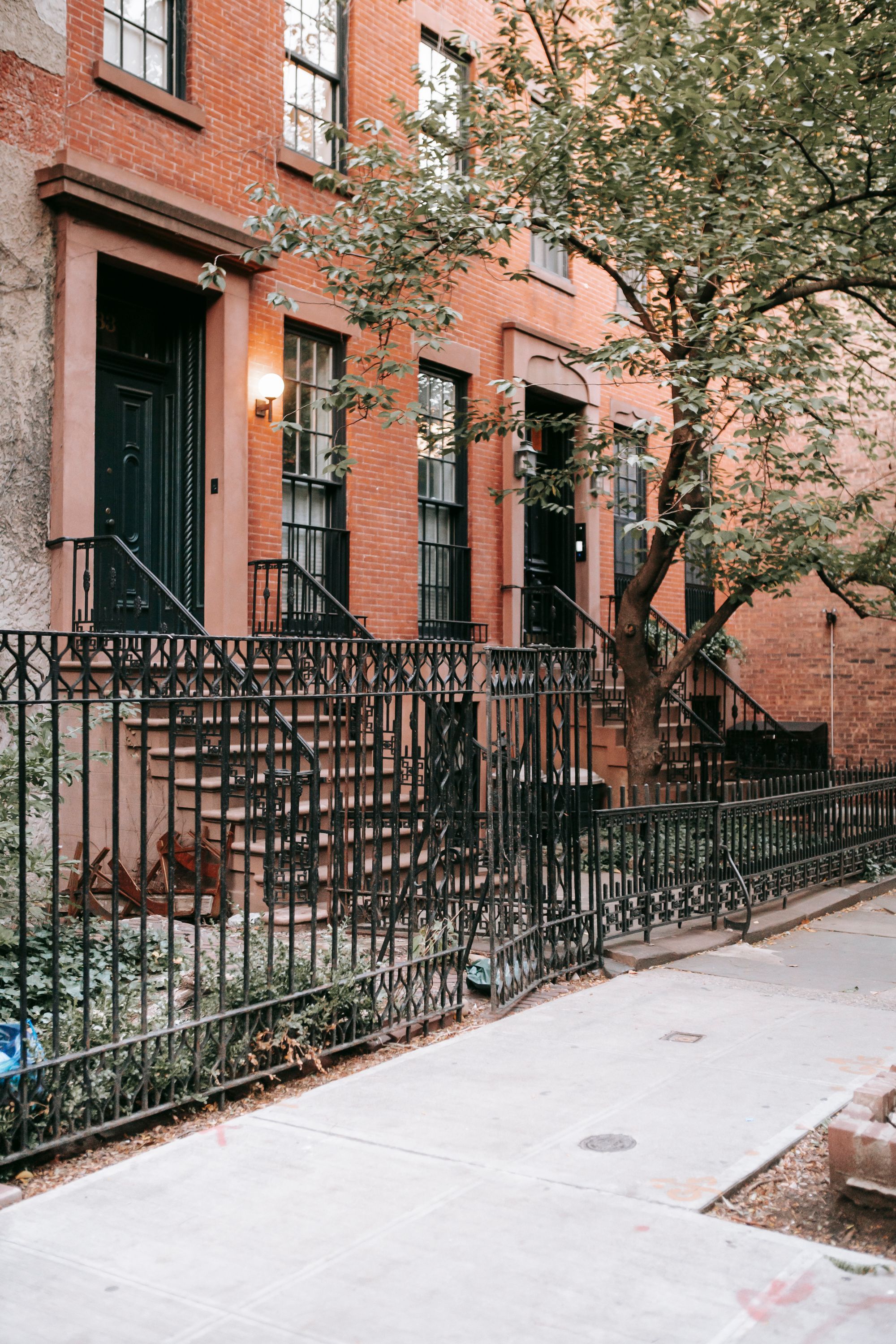 Brick townhouses with front steps behind an iron fence