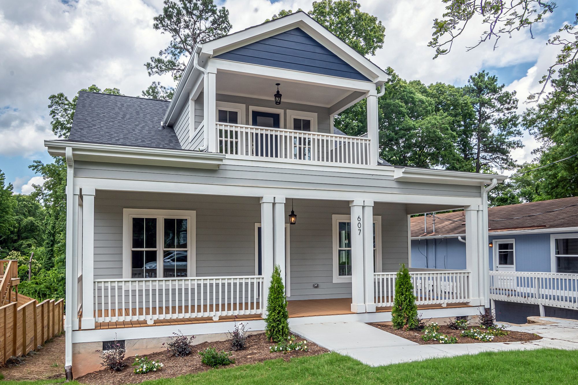 A white two-story house with a double front porch and a fresh lawn